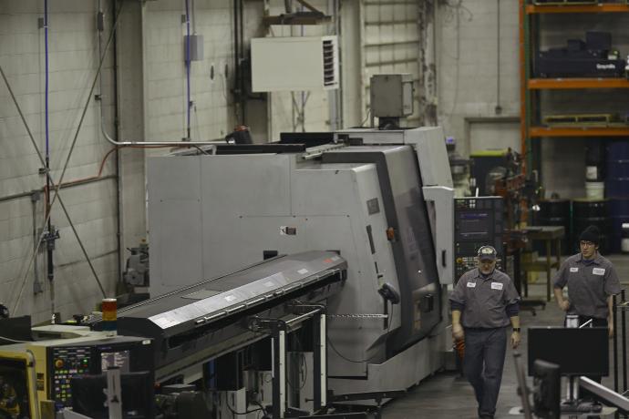 Coworkers walking side by side next to machine